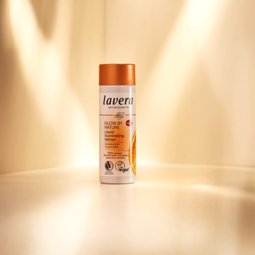 A can of Lavera Glow by Nature liquid illuminating primer with orange and white design.