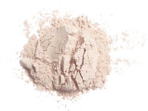 A soft, light pink powder spread on a white surface, with some parts more compact and cracked.
