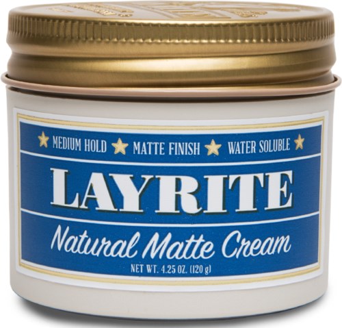 A white jar with a blue label and gold lid, labeled "Layrite Natural Matte Cream," indicating hair styling product.