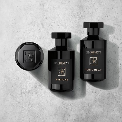 Drie zwarte flessen met Le Couvent-label, verschillende maten en een ronde dop, op een grijze achtergrond.