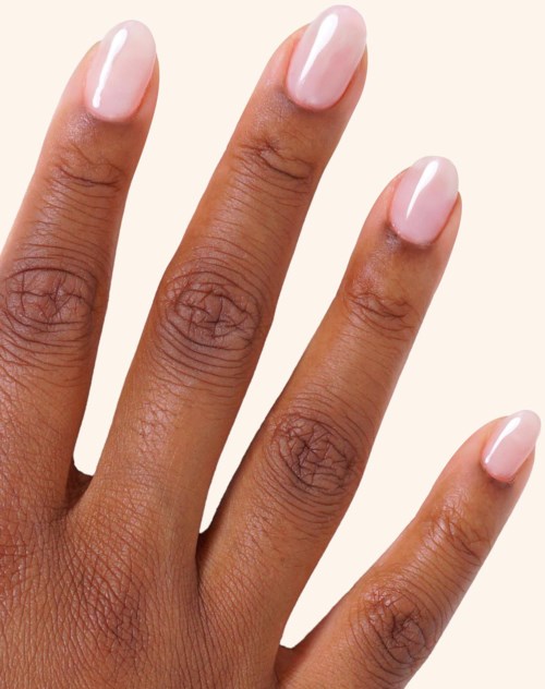 A hand with neatly painted light pink nails on a beige background.