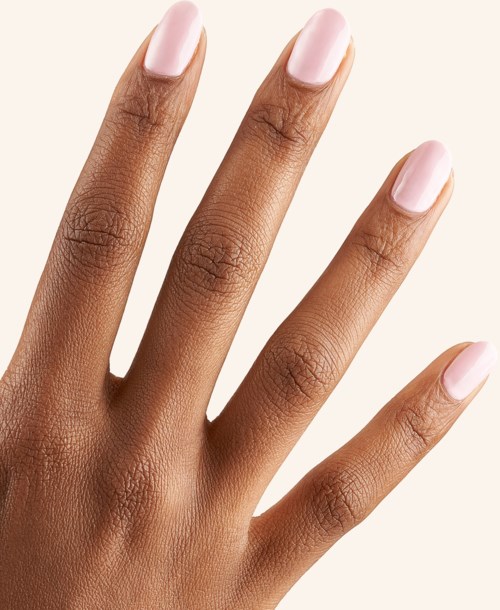 A hand with four fingers visible, nails painted light pink, skin smooth, against a plain background.