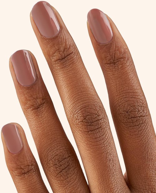 Four fingers with neatly painted nude-colored nails, close-up shot.