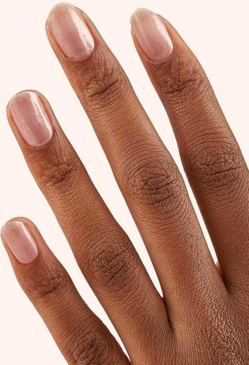 Close-up of a hand with well-groomed nails, skin is smooth and natural. Five fingers are visible against a light background.