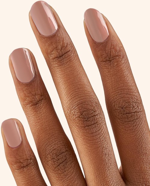 A close-up of a hand with three fingers showing, painted nails in a pinkish nude color.