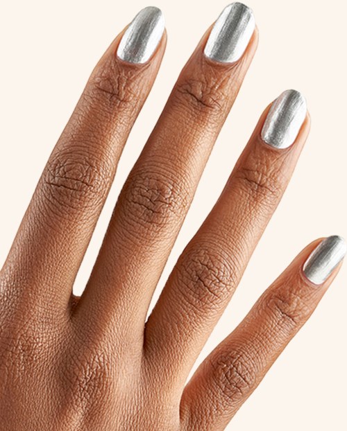 Hand with silver painted nails on a beige background. Close-up view of well-manicured fingers.