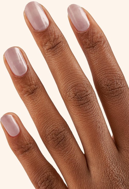 A hand with neatly painted light pink nails, showing skin details against a plain background.