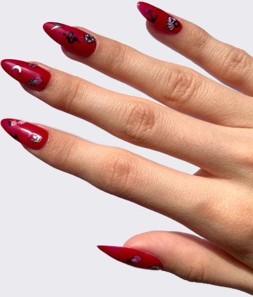 Nagellack i rött med små svarta och vita teckningar av skallar och hjärtan.