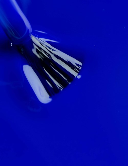 A close-up of a brush with white bristles on a blue surface.