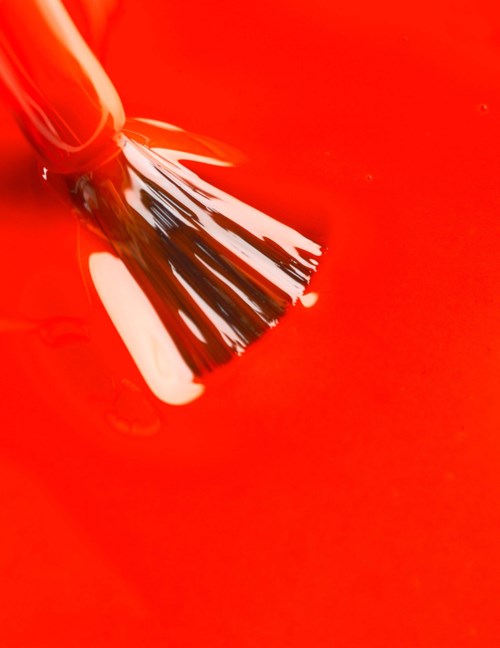 A paintbrush is dipped in bright red paint.