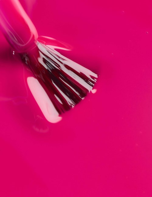 Rosa färg målas eller blandas med en pensel. Ytan är ljus rosa och glänsande.