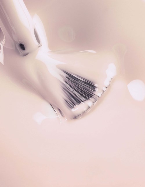 A brush is in soapy water, with bubbles and foam around it.