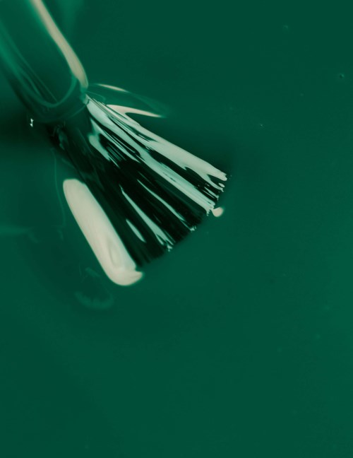 A makeup brush with black and white bristles resting on a dark green surface.