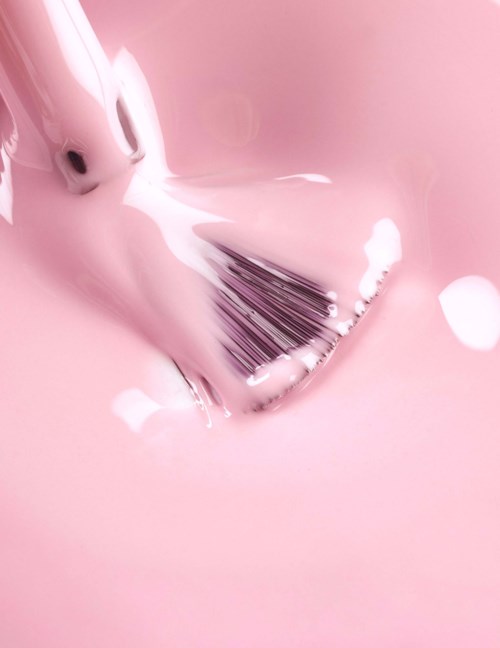 A brush is being cleaned with soapy pink water.