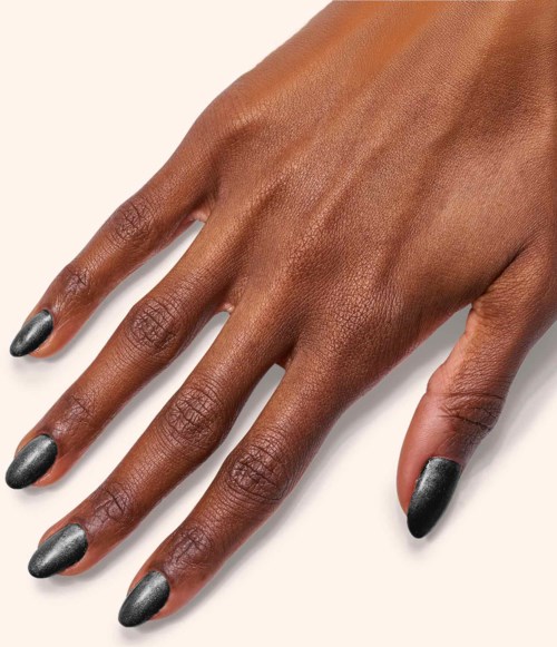 A hand with dark skin and nails painted in dark, shiny color, resting on a white surface.