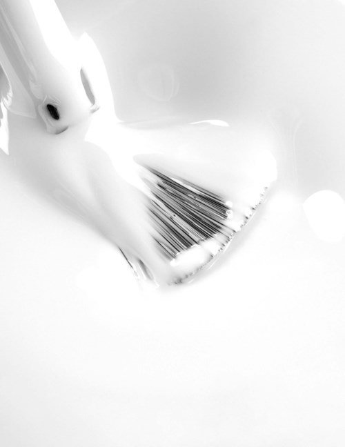 A white rabbit face with black eyes and nose, blurred focus, near a pile of black and white striped papers.