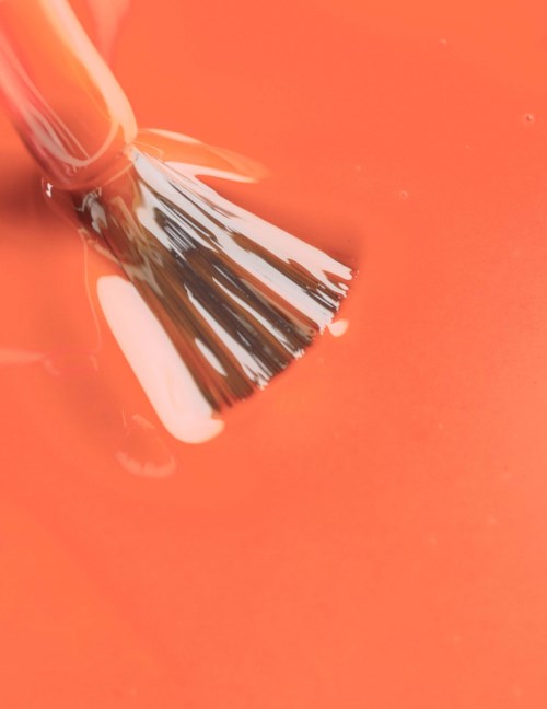 En pensel doppas i orange färg på en yta.