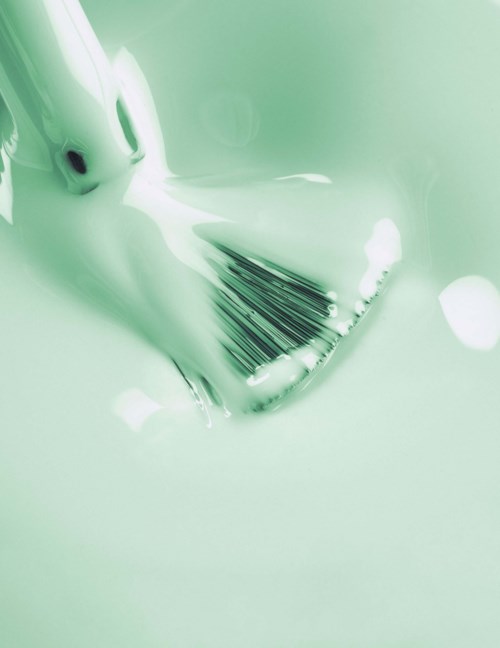 A toothbrush with toothpaste on it, placed in a greenish setting, possibly a bathroom sink or similar.