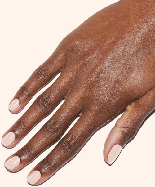 A hand with neatly painted light pink nails and smooth, dark skin.