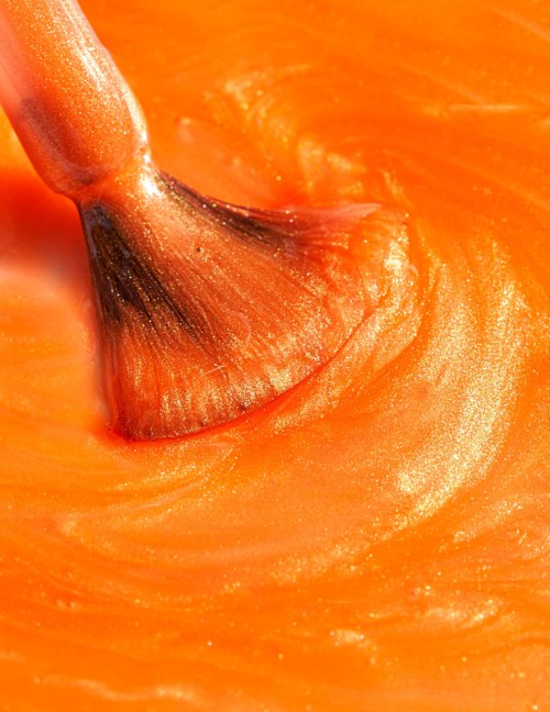 En borste blandar orangefärgade färger eller sås smidigt och skapar ett virvlande mönster.