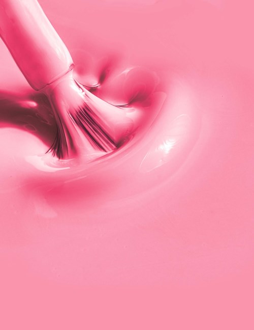 Pink liquid being stirred with a tool, creating ripples and bubbles.