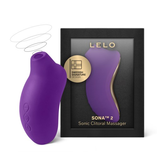 Violetti, kaareva laite edessä kehykseen laitettua laatikkoa, jossa on violetti muoto ja kultaisia yksityiskohtia, merkitty Sonic Clitoral Massageriksi.