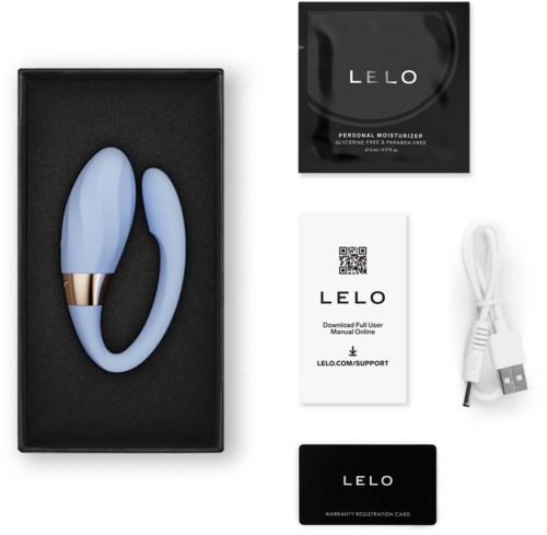 Blue silicone personal massager with gold accent, charging cable, and product information cards in packaging.