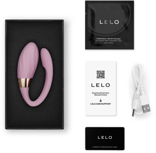 Pink silicone vibrator with a gold ring, in black box, alongside user manual, charging cable, warranty card, and product packaging.