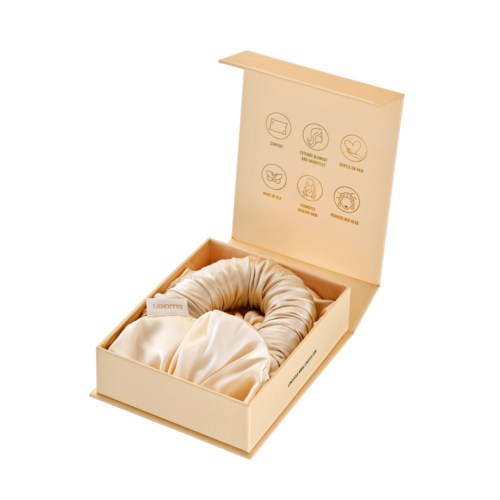 A beige box with symbols, containing a cream-colored cloth or fabric rolled up inside. The box lid is open.