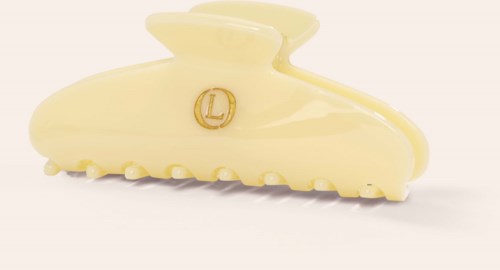 Een kleine, roomwitte haarclamp met een gouden L-logo en getextureerde ondertanden.