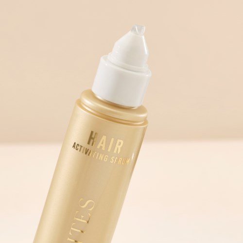 En gullfarget flaske merket 'Hair Activating Serum' med en hvit pumpe.