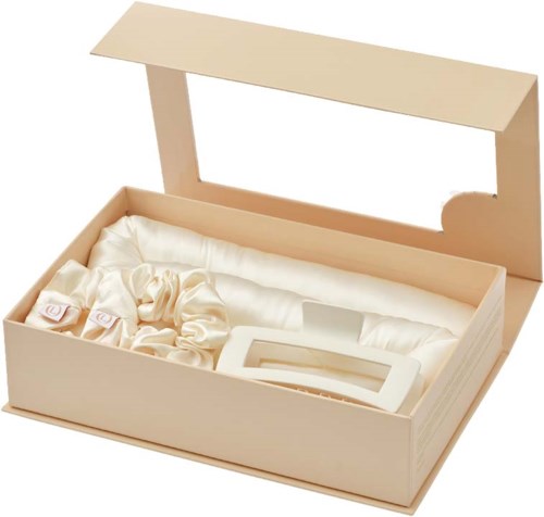A beige box with a lid, lined with satin fabric, contains a ring and jewelry pieces inside.