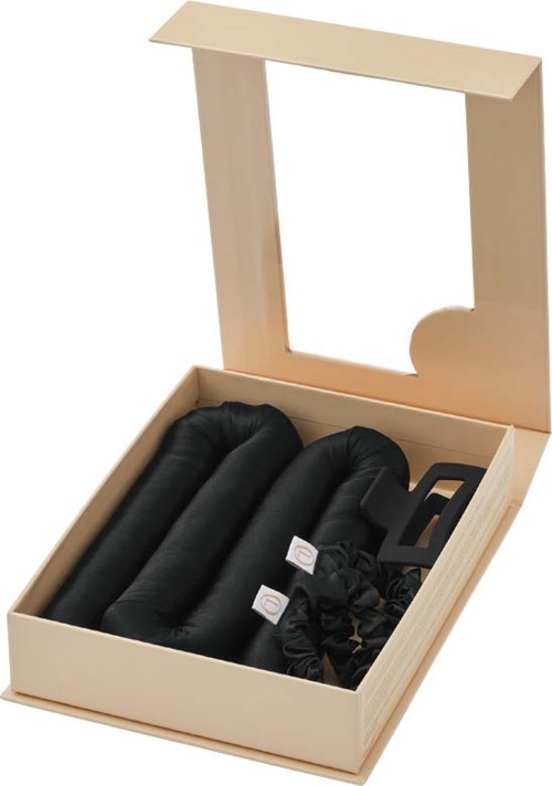 A wooden box contains three black neck pillows and some accessories, with a transparent lid open.