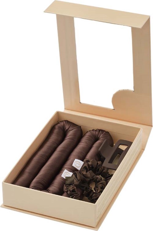 A cream-colored box with a mirror holds rolled brown socks and small ruffle accessories.