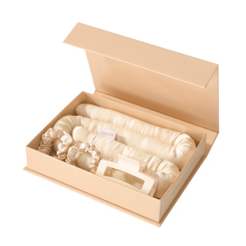 A cream-colored box with a long, rolled fabric and a small device inside, likely for skincare or beauty use.