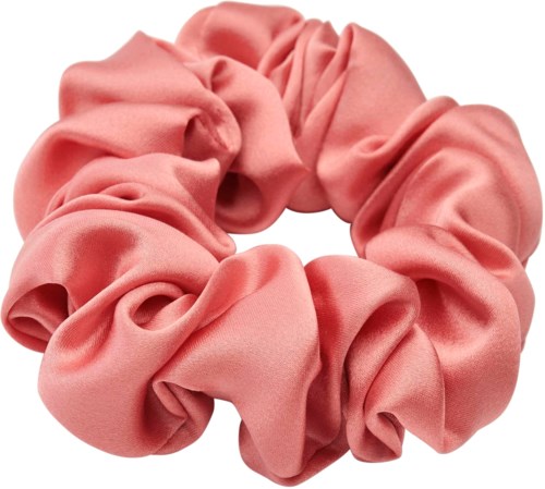 Ett rosa tygelock med ett hårband i scrunchie-stil, mjukt och samlat i en cirkulär form.