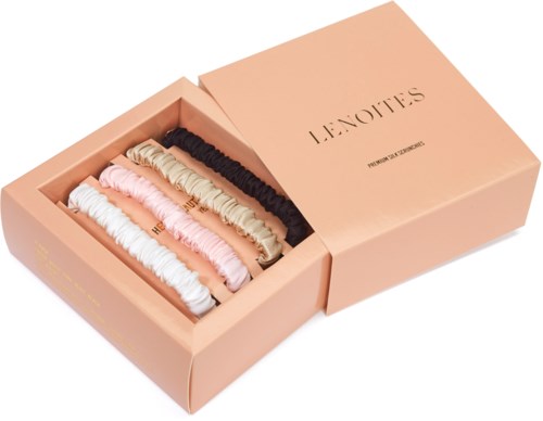 A pink box contains five different colored hairbands, neatly arranged inside. The box is partially open.
