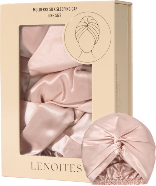 A box contains a pink satin sleeping cap with a twisted knot in front.