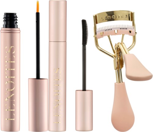 A set of makeup products including a mascara, a lipstick, a mascara wand, and an eyelash curler in pink and gold.