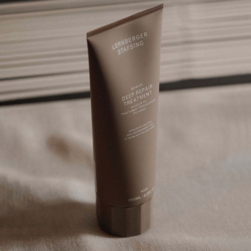 Ein brauner Tube Lernberger Stafsing Deep Repair Treatment mit weißen Text, auf beige Oberfläche.