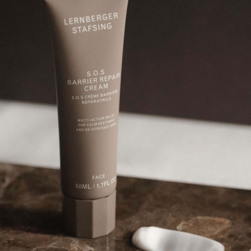 Eine Tube Lederberger SOS Barrier Repair Cream auf einer dunklen Oberfläche mit Text und einem kleinen weißen Gegenstand in der Nähe.