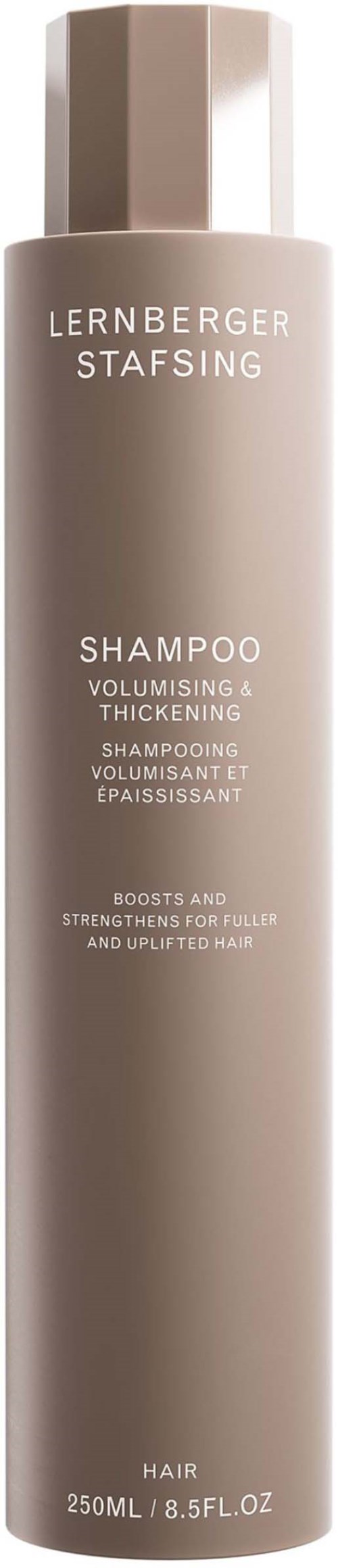 Eine lange, beige Flasche Shampoo mit weißem Text, der Volumen und Stärke für Haare verspricht.