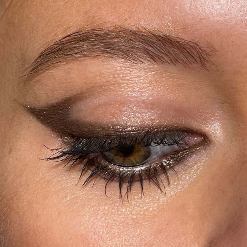 Close-up of a woman's eye with detailed makeup, including eyeliner and mascara, and groomed eyebrows.