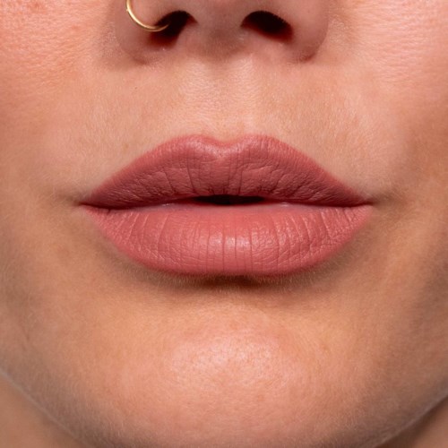 Close-up of lips with soft pink lipstick and a small nose piercing.