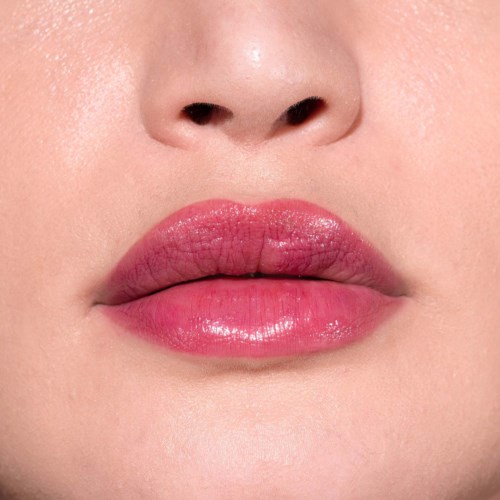 Nahaufnahme von Lippen mit rosa Glanz, zeigt glatte Haut und sanfte Schatten.