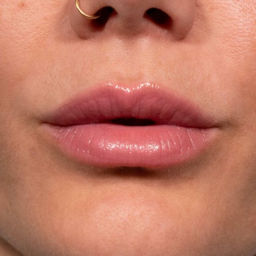 Nahaufnahme von Lippen mit glänzend pinkem Lippenstift und Nasenpiercing.