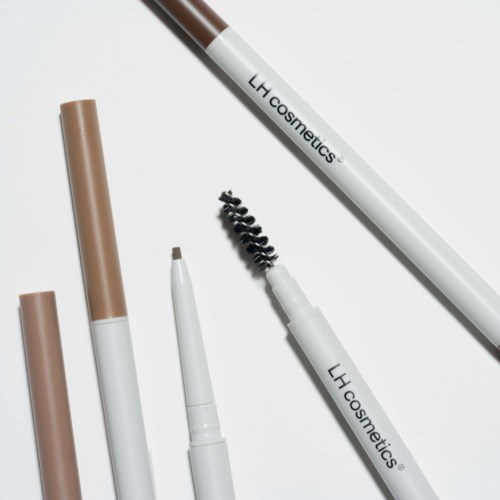 Makeup-penna och borstar är placerade på en vit bakgrund, främst i beige- och vita färger.