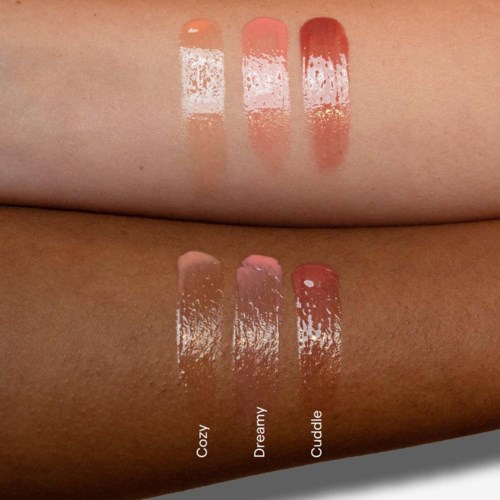 Drei Lipgloss namens Cozy, Dreamy, Cuddle sind auf Haut aufgetragen, zeigen Farbe und Textur.