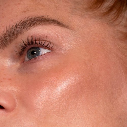Nahaufnahme eines Frauen Gesichts, zeigt ihr Auge und Teil der Wange mit klarer Haut und Make-up.