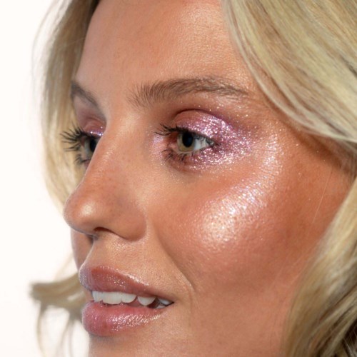 Nahaufnahme eines Frauengesichts mit glänzendem Make-up, betont Auge, Wange und Lippen.